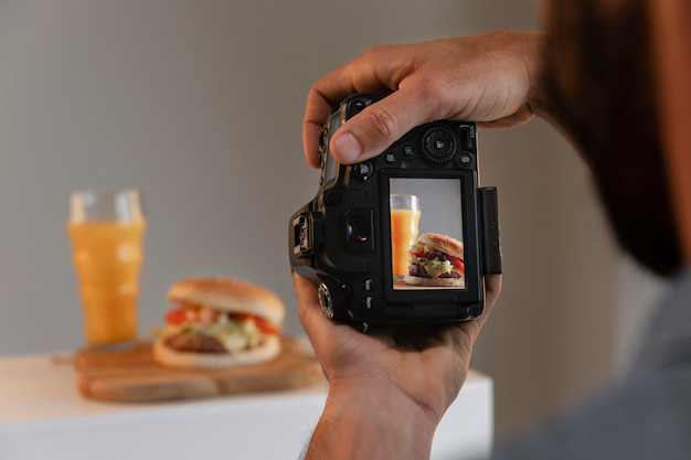 Photographer shooting a product photo of a burger and juice with a DSLR camera in a studio
